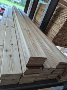 Stapel von Holzlatten in einem Lager, teilweise mit hellem, glattem Holz und einheitlich zugeschnitten.