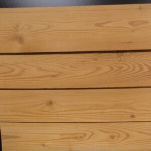Vier horizontale Holzplanken mit deutlicher Maserung vor einem schwarzen Hintergrund.