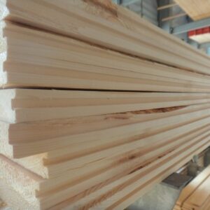 Ein Stapel Holzlatten in einer Holzwerkstatt, sauber geschnitten und gestapelt, mit einer glatten Oberfläche und einigen natürlichen Maserungen sichtbar.
