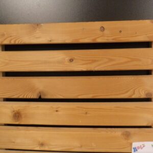Eine hölzerne Palette mit horizontalen Brettern, die mit Schrauben befestigt sind, vor einem dunklen Hintergrund. Unten rechts ist ein kleines Schild mit dem Wort 'Holz' und einem Logo sichtbar.