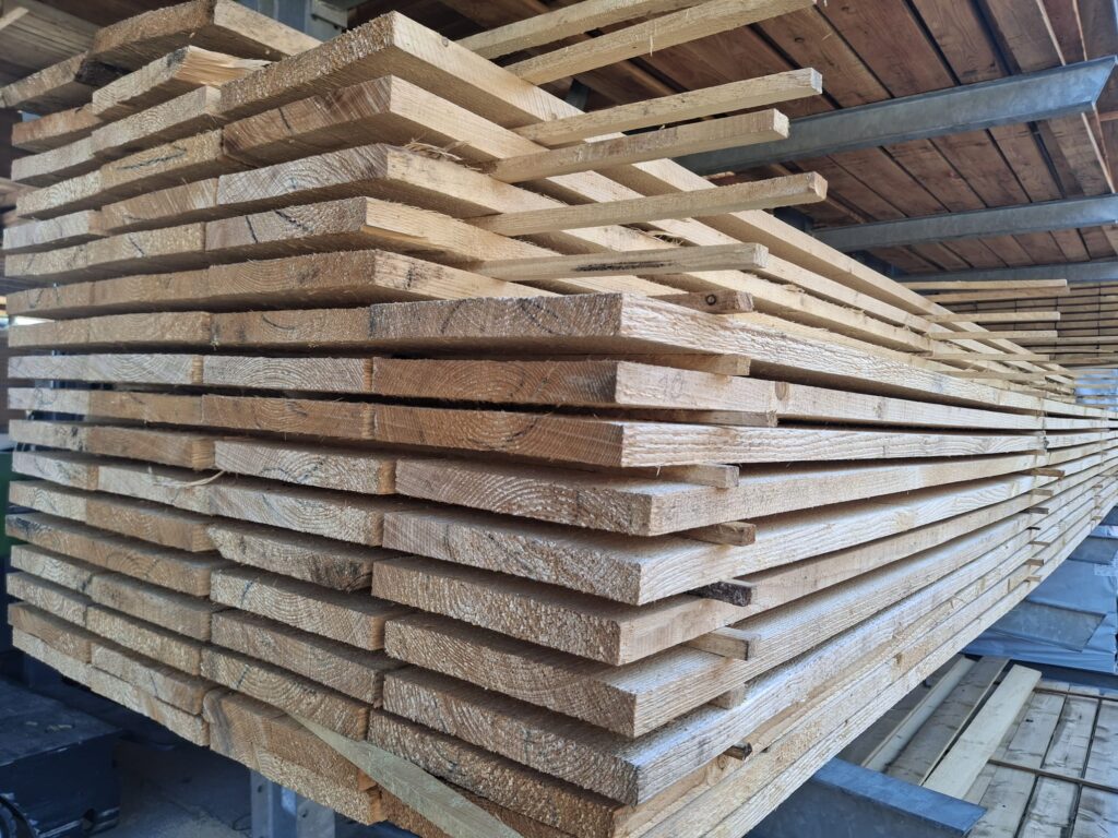 Ein Stapel gesägter Holzbretter, ordentlich gestapelt, in einem Lagerraum.