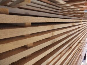 Gestapelte Bretter aus hellem Holz, lagenweise übereinander angeordnet, in einer Seitenansicht aufgenommen.