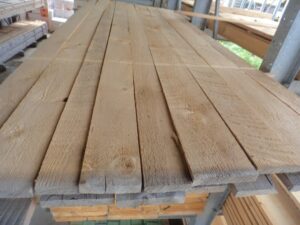 Ein Stapel von Holzbrettern in einem Lager oder einer Werkstatt, die parallel nebeneinander liegen.
