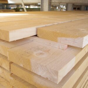 Ein Stapel unbehandelter Holzbohlen in einem Lagerraum, die sorgfältig übereinander gestapelt sind.