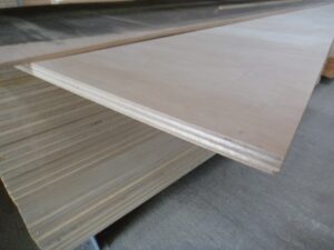 Plywood sheets stacked in a warehouse, showing their layered construction and smooth surface.
