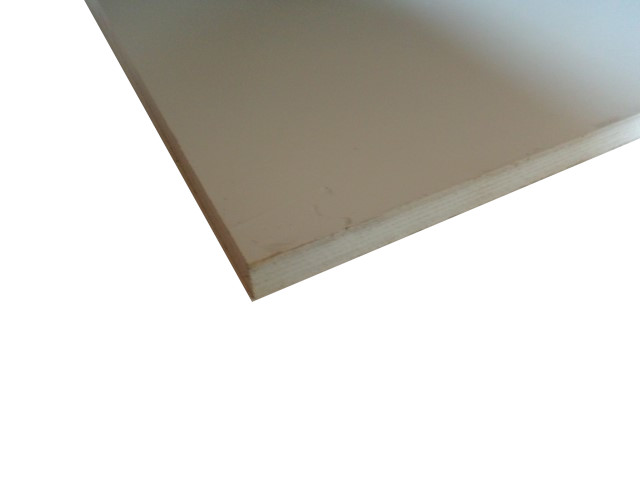 Nahaufnahme einer Kante einer Holz- oder Spanplatte mit einer glatten, hellen Oberfläche.