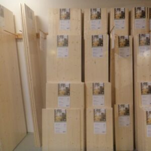Gestapelte Holzbretter in einem Baumarkt, mit Etiketten für Preise und Informationen auf der Vorderseite.