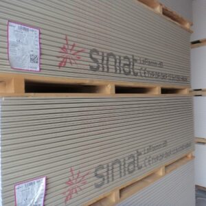 Stapel von Gipskartonplatten der Marke Sinat auf Holzpaletten gelagert.