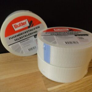 Drei Rollen selbstklebendes Fugendeckstreifenband der Marke Butler auf einem Holztisch.