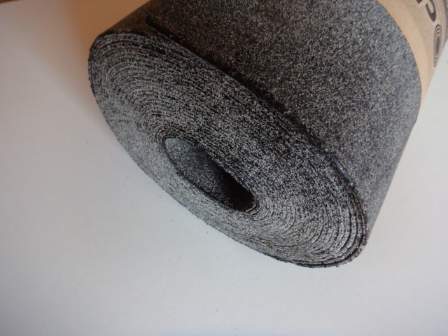 Nahaufnahme einer aufgerollten Rolle aus grobem, grau-schwarzem Material, die auf einem weißen Untergrund liegt.