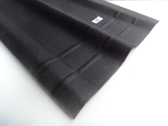 Detailaufnahme eines schwarzen, gerippten Gewebes auf weißem Hintergrund mit einem kleinen Etikett an der Oberfläche.