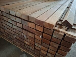 Gestapelte Holzbretter in einem Lagerraum, gleichmäßig geschnitten und parallel angeordnet.