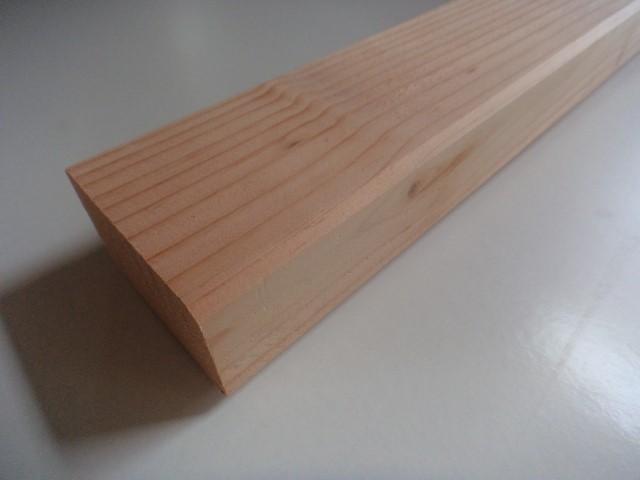 Nahaufnahme eines Stückes Holzlatte mit klar sichtbaren Maserungen auf einer glatten Oberfläche liegend.