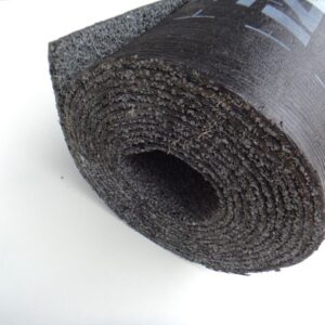 Eine Rolle aus schwarzem, gummiartigem Material, aufgerollt und auf einer flachen, weißen Oberfläche liegend.