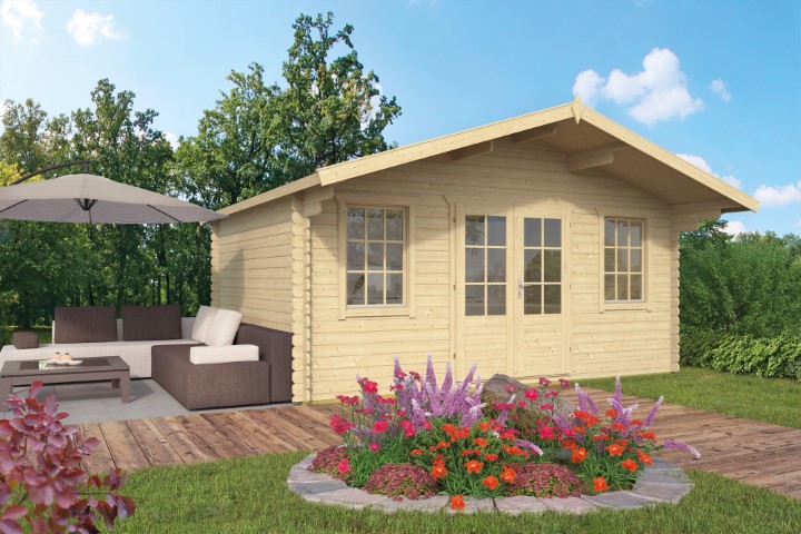 Ein helles Holzgartenhaus mit zwei Fenstern und einer Doppeltür steht auf einer Holzterrasse. Daneben befindet sich eine Sitzgruppe mit einem Sonnenschirm. Im Vordergrund blühen bunte Blumen, und im Hintergrund sind grüne Bäume zu sehen.