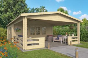 Ein helles Holz-Gartenhaus mit überdachter Terrasse, ausgestattet mit Sitzmöbeln und blühenden Pflanzen, befindet sich in einer grünen Umgebung mit Blumenbeeten und Bäumen im Hintergrund.