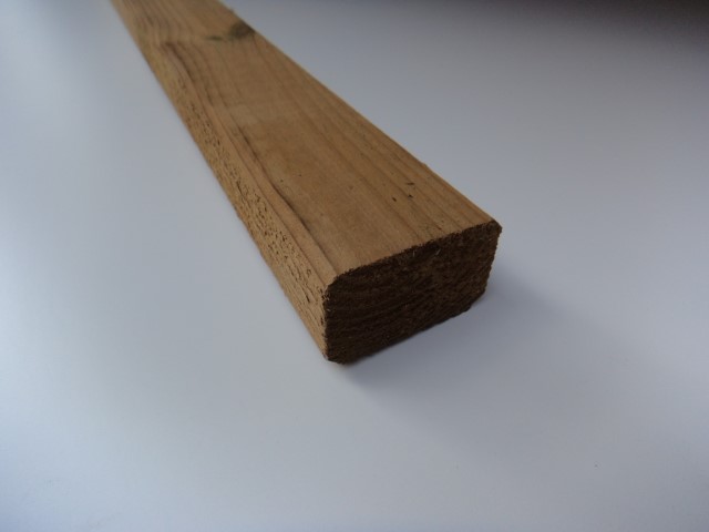 Ein einzelnes Holzbrett auf einer weißen Fläche, mit einer sichtbaren Maserung und glatter Oberfläche.