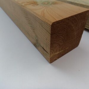 Ein grobes Holzbrett mit sichtbaren Jahresringen und einer rechteckigen Form liegt auf einer hellen Oberfläche.