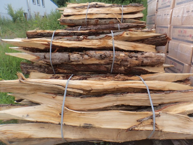 Ein Stapel von gebündeltem Brennholz aus gespaltenen Holzscheiten mit Plastikbändern gesichert, im Freien gelagert.
