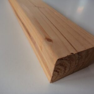 Nahaufnahme eines abgeschrägten Holzprofils auf einem weißen Untergrund.