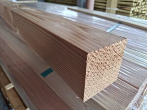 Ein Stapel von zugesägten Holzbalken in einem Lager, mit einem klaren Blick auf die glatte Textur und die scharfen Kanten des vordersten Balkens.