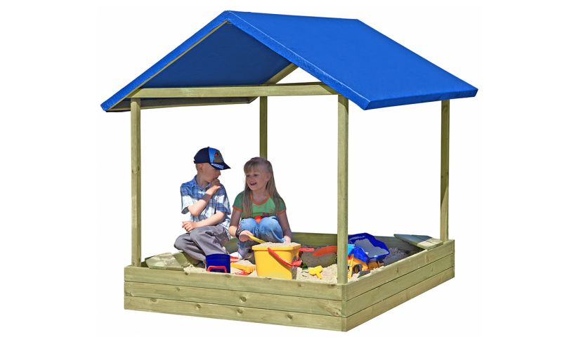 Zwei Kinder spielen in einem Sandkasten mit blauem Dach.