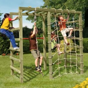 Kinder spielen auf einem Holz-Klettergerüst im Garten, eines klettert ein Seil hoch, während zwei andere auf einem Netz klettern; im Hintergrund sind Bäume und ein bunter Ball zu sehen.