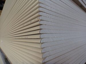 Ein Stapel von Gipskartonplatten, die gleichmäßig aufeinander liegen, mit sichtbaren Kanten und identischen Größen.