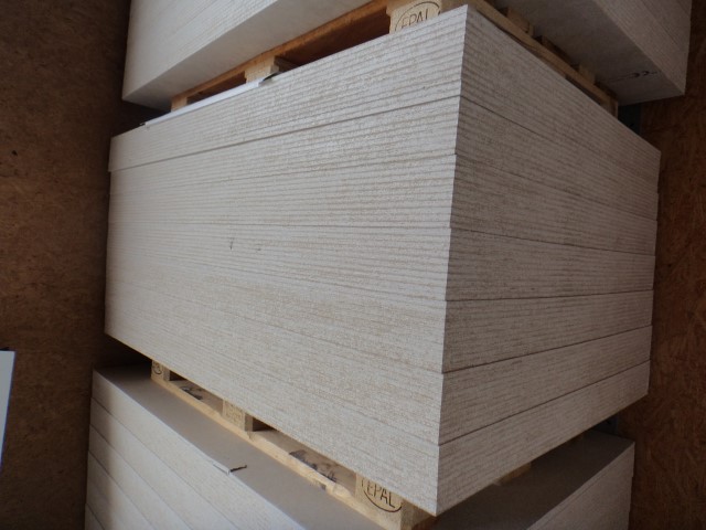 Ein Stapel weißer Holzplatten auf einer Palette gestapelt in einem Lagerraum.