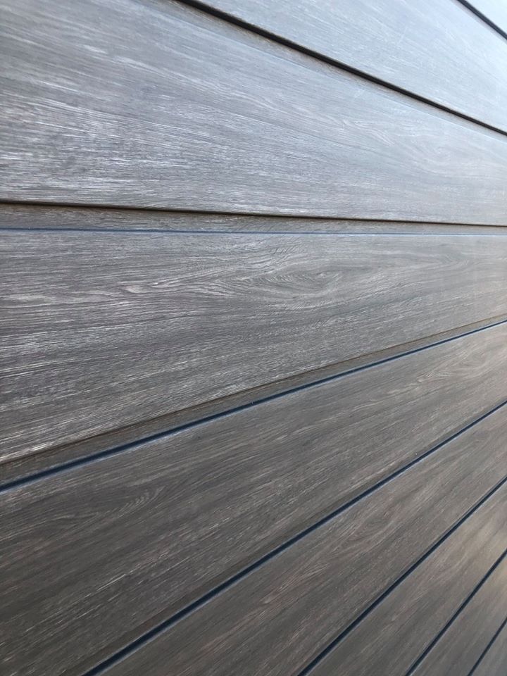 Holzwand mit horizontalen Paneelen in einem dunklen, grauen Farbton mit sichtbarer Maserung.