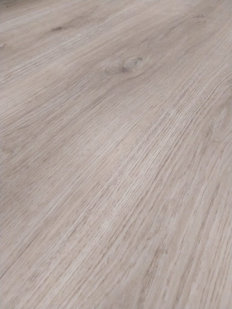 Nahaufnahme einer hellen Holzoberfläche mit sichtbarer Maserung und Knoten.