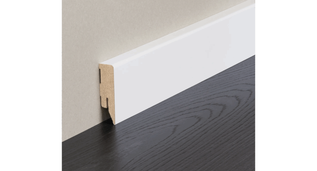 Ein weißes Sockelleistenprofil aus MDF, das an einer Wand montiert ist, über einem dunklen Holzboden.