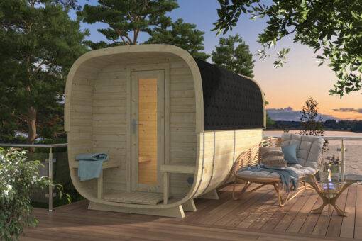 Eine moderne Fasssauna auf einer Terrasse mit Blick auf einen See bei Sonnenuntergang, umgeben von Bäumen.