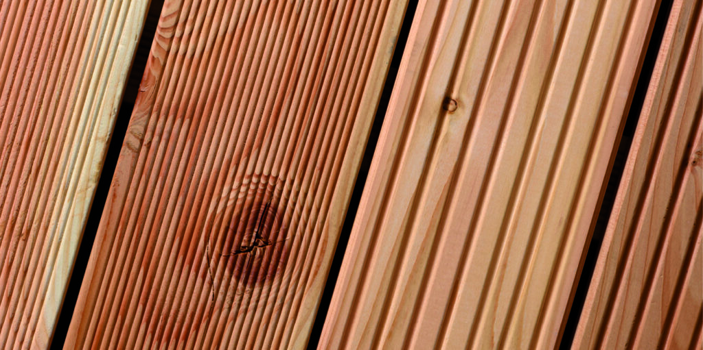 Nahaufnahme von holzfarbenen Terrassendielen mit feinen Rillen und einer Aststruktur.