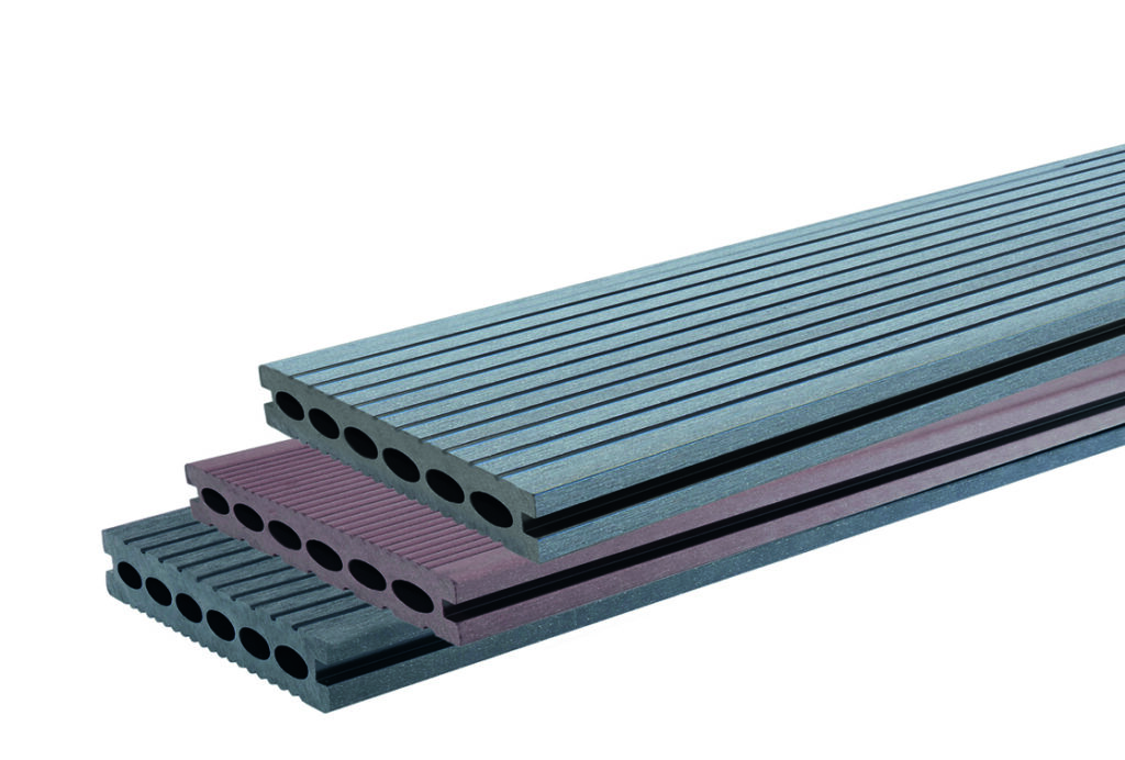 Drei gestapelte Terrassendielen in verschiedenen Farben mit gerillter Oberfläche und Hohlräumen in der Mitte.