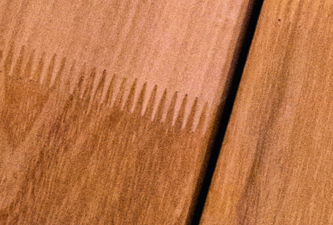 Nahaufnahme einer Holzoberfläche mit geometrischen Mustern und parallelen Linien.