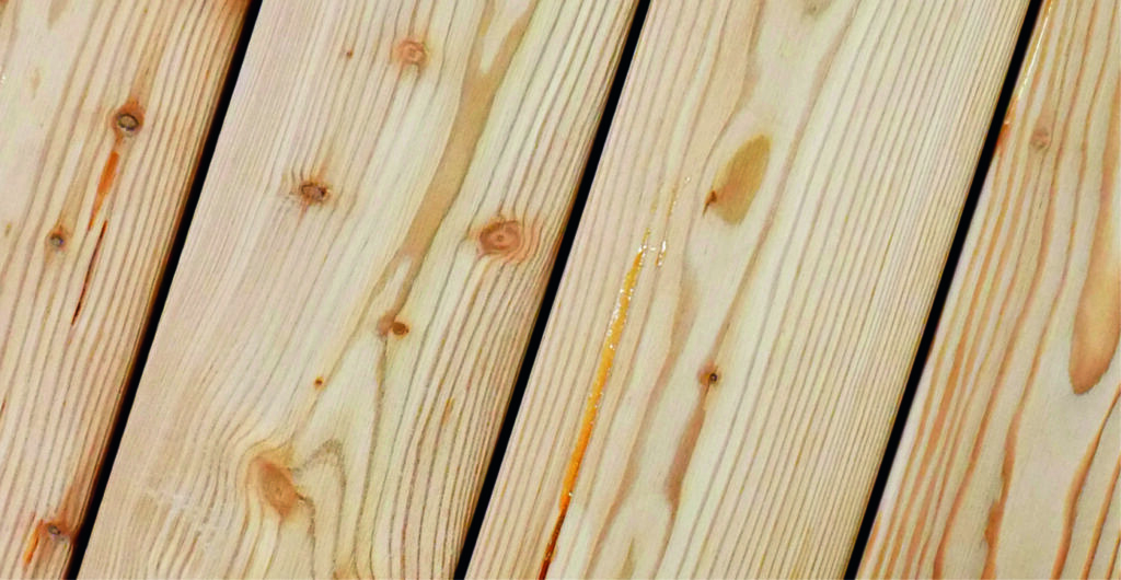 Holzdielen mit sichtbarer Maserung und einigen Astlöchern, in hellem Naturton.