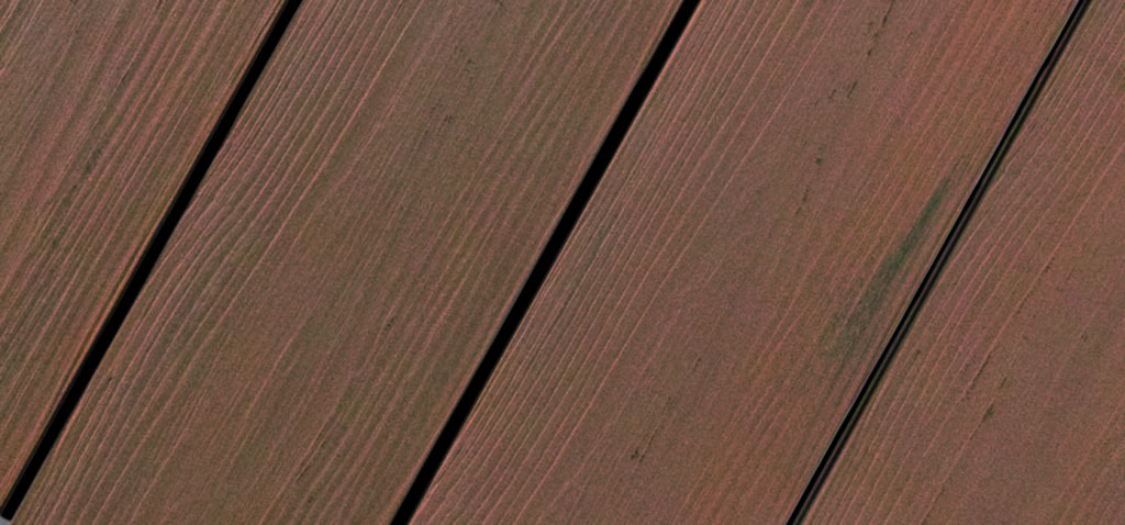 Nahaufnahme von diagonal verlegten Holzdielen mit rötlich-brauner Färbung und feiner Maserung.