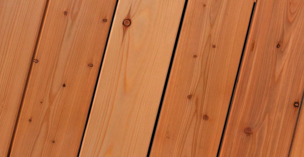 Braune Holzplanken mit sichtbarer Maserung und Astlöchern in diagonaler Ausrichtung.