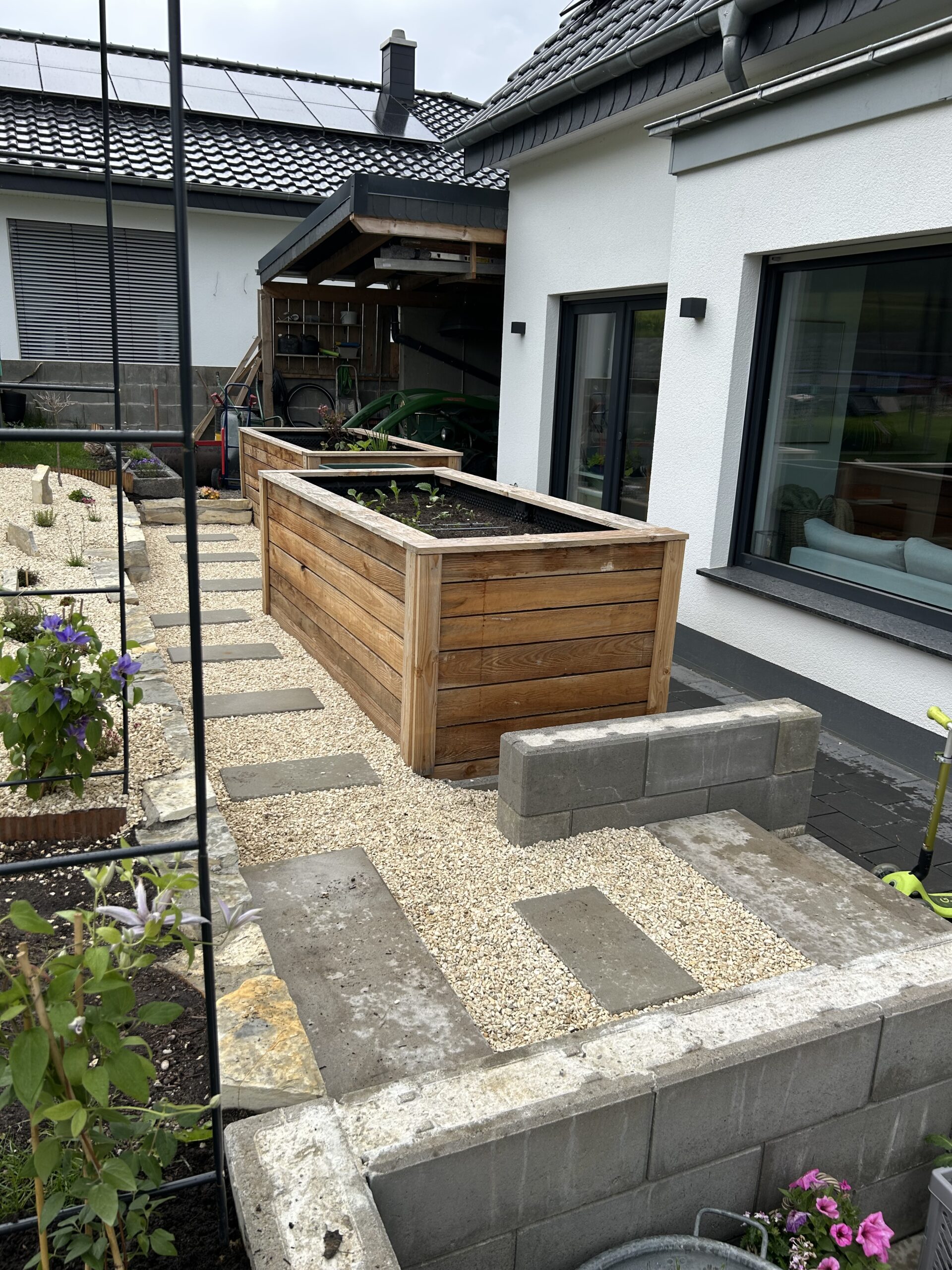 Mittelgroßes Hochbeet aus Holz in einem gepflegten Garten neben einem modernen Haus.
